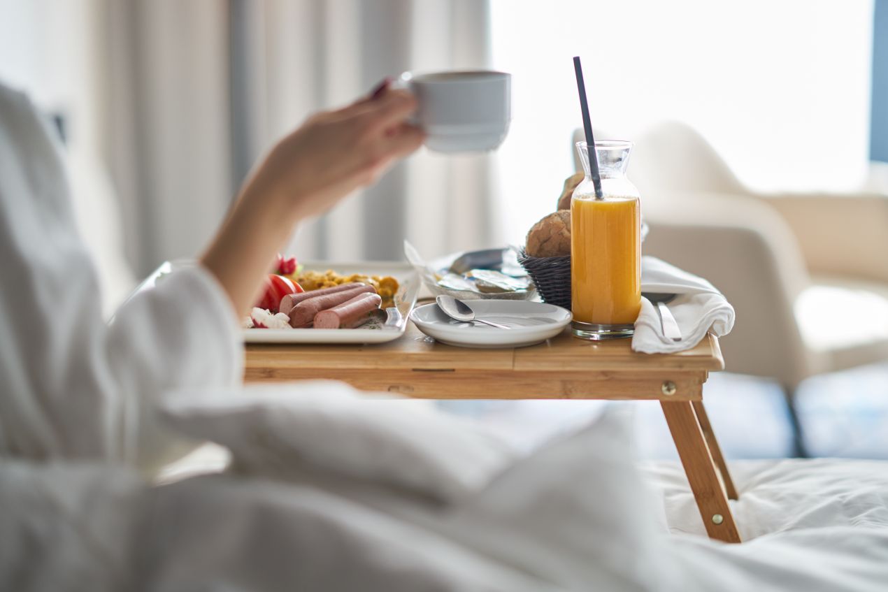 Fruestueckstablett mit Orangensaft, Kaffee und Broetchen auf einem Bett im Wellnesshotel Bayern