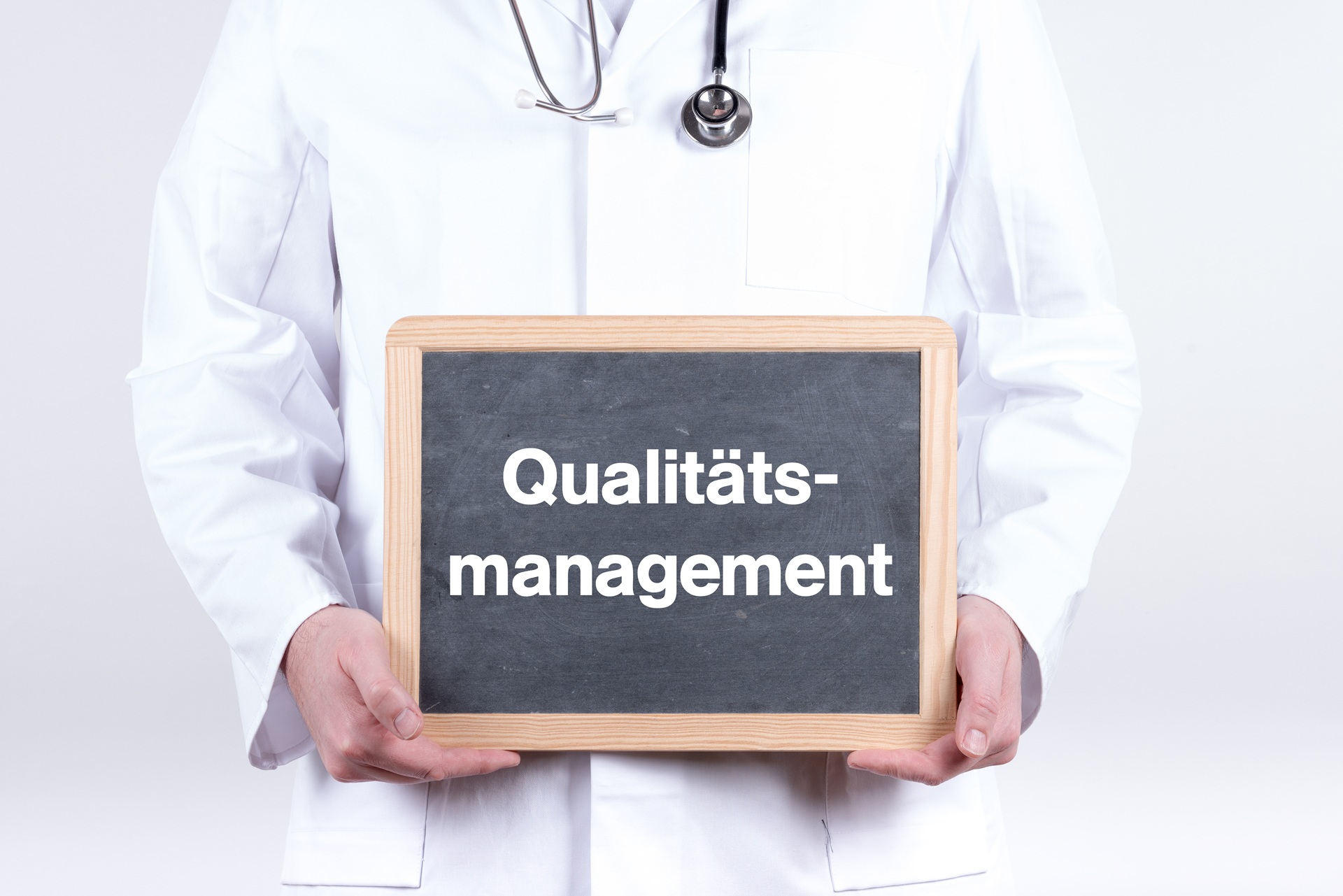 Arzt hält Tafel mit Qualitätsmanagement-Schriftzug | medizinische Übersetzung